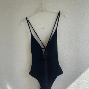 Svart baddräkt med djup rygg och knyt - Säljer en svart baddräkt djup v-ringning och knyt- och snörningsdetaljer i ryggen. Kuporna är vadderade 🖤☀️Passar S/M