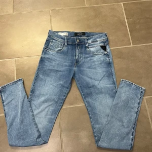 Replay Anbass ljusblå jeans - Säljer ett par Replay Anbass jeans i ljusblå tvätt med klassisk femficksdesign och normal passform. Byxorna har dragkedjegylf och snygga detaljer på bakfickorna. Perfekta för dig som gillar stilrena jeans med modern look.