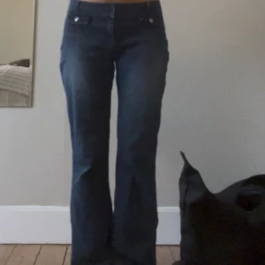 Blå bootcut jeans - Säljer ett par klassiska blå bootcut jeans med normal passform och låg midja. Jeansen har coola fickor med dragkedja och knapp framtill. Perfekta för dig som gillar en tidlös denimlook. OBS INSYDDA I MIDJAN AV MIG OCH UPPSYDDA SÅ DE PASSAR MIG SOM ÄR 160!