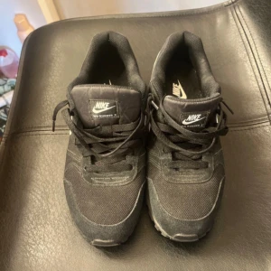 Skor - Säljer ett par svarta Nike sneakers i  klassisk vit&swoosh på sidan. Skorna har snörning och rund tå, perfekt för dig som gillar en sportig och stilren look. Passar till många olika outfits. Använda 2 ggr💗