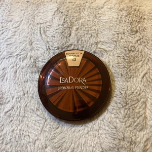 Isadora Bronzing Powder 43 Terracotta Bronze - Säljer ett Isadora Bronzing Powder i nyansen 43 Terracotta Bronze. Kommer i en rund brun plastförpackning med spegel i locket. Ger en varm, solkysst look med lätt skimmer. Perfekt för att framhäva ansiktskonturer och ge glow. Köpt nyligen, inte använd. Insåg bara att jag hade för många.