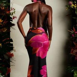 Svart långklänning med stora blommor från Murci - Säljer en svart långklänning från MURCI med stora rosa och orange blommor. Klänningen har djup v-ringning, öppen rygg och halterneck. Sval och följsam passform, perfekt för sommarkvällar. Materialet känns lätt och smidigt mot huden och går att knyta fast band baksidan så tajt man vill ha. Jag har storlek 36/ S och denna passa perfekt på mig. Använd endast 1 gång på semester, är i helt nytt skick, inga defekter/fel. 