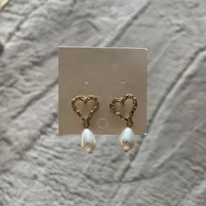 Guldiga hjärtformade örhängen med pärlor - Säljer en par så fina pärlörhängen med hjärtan på! Helt oanvända🩷