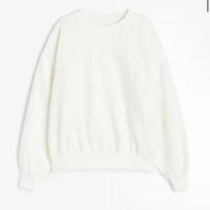 Vit sweatshirt med rund hals - En basic vit sweatshirt med rund hals och långa ärmar. Tröjan har ribbade muddar vid ärmslut och nederkant för en klassisk look. Perfekt att matcha med jeans eller mjukisbyxor.