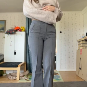 Grå kostymbyxor med pressveck - Snygga grå kostymbyxor med hög midja och raka ben. Byxorna har pressveck framtill och en diskret ficka bak. Perfekta för en stilren look och passar till många olika outfits. Jag är 1.63 och tycker de blir lite för korta på mig men det kan också vara en preferens sak☺️460 ny pris