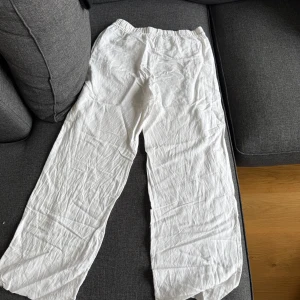 Vita linnebyxor med resårmidja - Säljer ett par vita linnebyxor i storlek S. Byxorna har rak passform och resår i midjan för extra komfort. Perfekta för varma dagar och enkla att matcha med olika toppar.
