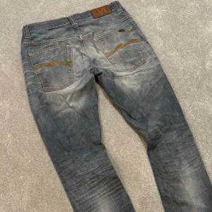 Nudie jeans - Tja! Säljer dessa asfeta ljusblå/grå Nudie jeansen med riktigt najs tvätt! Slimfit passform. Jeansen är i gott skick, syns att de använts men på ett snyggt sätt! Size 32/34. Skriv vid frågor! 