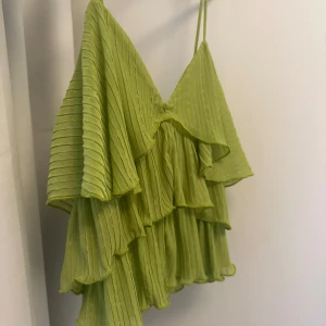 Grönt volang linne - Grönt linne med volanger och smala band från Zara, strl S. Våldigt luftig och skön, perfekt för sommaren. Endast använd fåtal gånger!