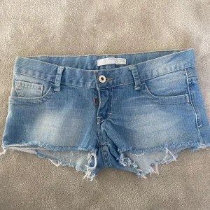 Ljusblå jeansshorts med fransar - Säljer ett par ljusblåa lågmidjade jeansshorts från Outfitters Nation. De har råa fransade kanter, klassisk femficksdesign och hällor för bälte. Köpta från Vinted.
