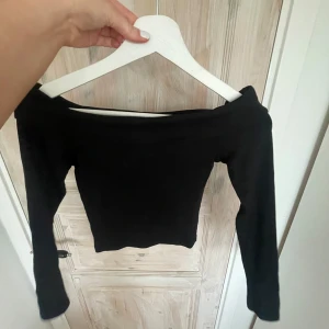 Svart offshoulder topp - Säljer en svart offshoulder topp med lång ärm. Snygg och enkel modell som passar perfekt till många olika outfits. Toppens material känns stretchigt och följsamt.