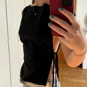Svart ärmlös topp med knyt i sidan - Säljer denna snygga o stilrena topp från Weekday. Knutarna i sidan går att knyta upp o justera, helt oanvänd🖤💖Öppen för prisförslag, ej under 250kr😊
