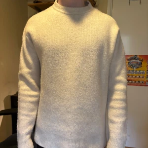 Vit stickad tröja med rund hals - Säljer en enkel och stilren vit stickad tröja med rund hals. Tröjan har lång ärm och en klassisk passform som funkar till många olika outfits. Perfekt för kyligare dagar!