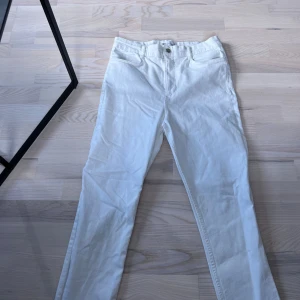 Vita jeansbyxor från Zara - Säljer ett par vita jeansbyxor från Zara i storlek L. Byxorna har klassisk femficksdesign, raka ben och normal passform. Perfekta att styla med en enkel topp eller stickad tröja.