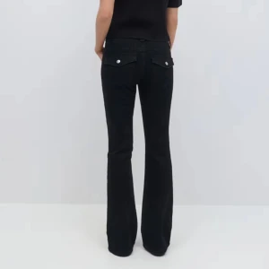 Svarta bootcut jeans - Snygga svarta bootcut jeans med klassisk femficksdesign och knappdetaljer på bakfickorna. 