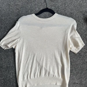 Vit kortärmad stickad tröja - Säljer en enkel och stilren vit stickad tröja med korta ärmar och rund halsringning. Perfekt att matcha med jeans eller kjol! Bra skick!!