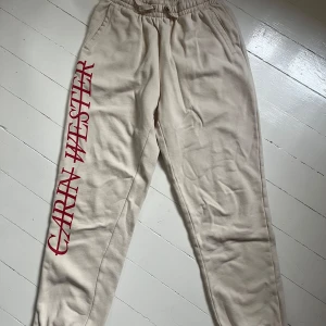 Beige mjukisbyxor från Carin Wester - Beiga mjukisbyxor från Carin Wester med resår i midjan och fickor. Stora röda bokstäver längs ena benet. Perfekta för en avslappnad stil och riktigt sköna att ha på sig. Finns matchande sweatshirt som jag säljer också. Kan fås billigare om de köps ihop. Skriv för fler bilder💞