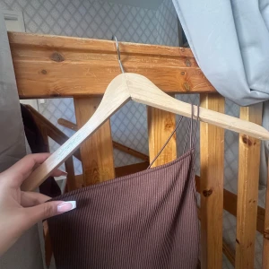 Brun ribbad klänning med smala axelband - Säljer en brun ribbad klänning med smala axelband och figurnära passform. Klänningen har en enkel och stilren design med stretchigt material som sitter snyggt på kroppen. Perfekt för dig som gillar minimalistisk stil.