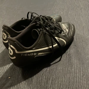 Nike Tiempo svarta fotbollsskor - Säljer ett par svarta Nike Tiempo fotbollsskor med klassisk vit swoosh och coola detaljer på. 
