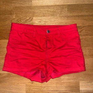 Röda shorts med fickor och dragkedja - Snygga röda shorts med klassisk femficksdesign, bälteshällor och dragkedja framtill. Modellen är kort och har en enkel, stilren look som passar perfekt till varma dagar. Gjorda i mjuk bomull för skön känsla och bra passform.