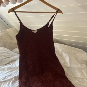 Rostbrun lång klänning från H&M - Supersnygg rostbrun lång klänning från H&M med smala axelband och strukturerat tyg. Klänningen har en enkel, rak passform och är perfekt för dig som gillar en stilren look med lite edge. Materialet känns mjukt och har en cool textur.(säljer även på vinted!) bara använd en gång💕