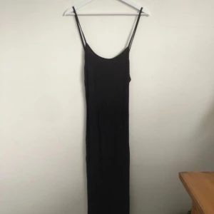 Svart långklänning  - En svart långklänning från NLY Trend i storlek XS. Klänningen har smala axelband och en rak, figurnära passform med djup urringning på fram och bak.