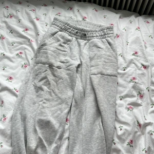 Grå mjukisbyxor från 157 - Superbekväma ljusgrå mjukisbyxor från 157 med bred resår i midjan och stora fickor framtill. Perfekta för chill dagar eller när du vill ha något riktigt skönt på dig. Tillverkade i mjuk bomullsmix. Lite fettfläckar och inga snören därför säljs de billigt
