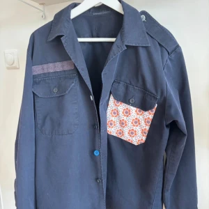 Mörkblå overshirt Iconic By Sophie - Säljer denna fina vintage jacka frän svenska flottan, 1990-tal. En riktig pärla för samlare eller stilmedvetna! En av fickorna har blivit unikt customiserad av Sophie - en fransk designer med öga för detaljer. Jackan köptes i en fantastisk vintagebutik i Saint-Tropez. Ett unikt plagg med bäde historia och personlighet!