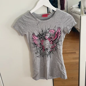 T-shirt med tryck - Snygg grå t-shirt från Miss Snob med coolt tryck av hjärta, vingar och tärningar i rosa och svart. Modellen är tight och kortare i passformen, perfekt till jeans eller shorts. Pris kan diskuteras!💕💕