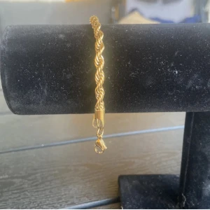 Guldigt tvinnat armband - Snyggt armband i guldig färg med tvinnad kedja, armbandet är i nytt skick, armbandet är inte i riktigt guld men är gjord av stål,18cm, 50kr
