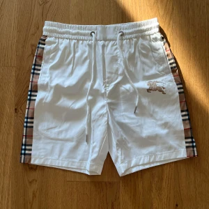 Vita BB shorts  - Snygga vita BB shorts som är perfekta till sommaren med randiga sträck på sidan.