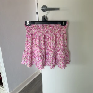 Blommig volangkjol i rosa och vit - Supersöt kort volangkjol med blommigt mönster i rosa och vitt. Kjolen har stretch i midjan och är perfekt i längd! Den är ifrån Gina Tricot och är i storlek XXS 🙏🏼