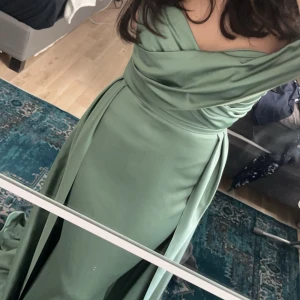 Ljusgrön långklänning med drapering - Säljer en elegant ljusgrön långklänning med vacker drapering över axlarna och figurnära passform. Klänningen har en svepande kjol och offshoulder-design som ger en lyxig känsla. Perfekt för dig som vill sticka ut på bal eller fest!   Avdnända en gång, väldigt bra skick. Skriv privat för flera bilder, pris går att diskutera.