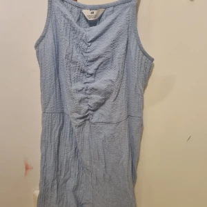 Ljusblå ärmlös jumpsuit H&M - Superfin ljusblå jumpsuit från H&M med skrynklig struktur och snygg rynkdetalj framtill. Ärmlös modell med avslappnad passform, perfekt för varma dagar. Enkel och stilren design som är lätt att matcha.