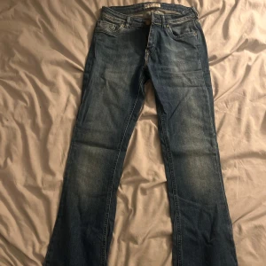 Blå bootcut jeans från Lee - Snygga blå jeans från Lee med klassisk bootcut-passform och lite slitna detaljer. Jeansen har fem fickor, Lee-lapp bak i midjan och snyggt tvättad denim. 