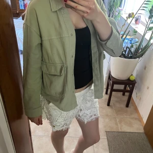 Beige overshirt med fickor - Snygg khaki overshirt med stora fickor framtill och knappar hela vägen. Jackan har en avslappnad passform och är tillverkad i ett mjukt bomullstyg. Perfekt att slänga över en t-shirt eller linne för en chill look.