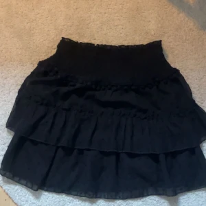 Svart volangkjol💓 - Supersöt svart kortkjol med flera volanger och bred smock i midjan🤍