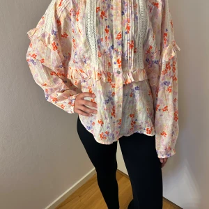blommig blus - En jättesöt blommig blus från indiska med värde på 600 kr. Den har aldrig använts. tröjan är storlek M, den sitter lite stort på modellen som vanligt vis bär xs.