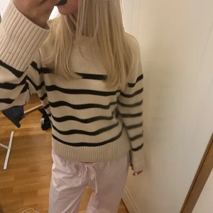 Randig beige stickad tröja - Supermysig stickad tröja i beige med svarta horisontella ränder. Tröjan har rund halsringning, breda ribbade muddar och lång ärm. Perfekt för sommarkvällar och höstdagar .pris kan diskuteras 