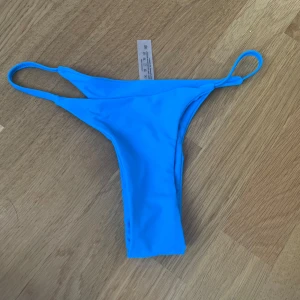 SHEIN bikiniunderdel  - Snygg blå bikiniunderdel i stringmodell med smala band i sidorna. Tillverkad i stretchigt material som består av 80% polyamid och 20% elastan. Perfekt för dig som vill ha en enkel och stilren look på stranden. SHEIN
