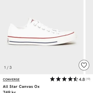 Vita Converse All Star Canvas Ox - Klassiska vita Converse All Star Canvas Ox med lågt skaft, snörning och platt sula. Skorna har en röd och blå rand längs sulan och är tillverkade i canvas. Perfekta för en avslappnad och stilren look. Helt nya köpa för 749