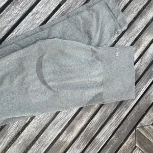 Grå leggings från NVGTN - Snygga grå leggings från NVGTN med hög midja och bred resår. De är tillverkade i ett stretchigt material som sitter tight och formar sig efter kroppen. Perfekta för träning eller chill. Diskret logga på linningen.