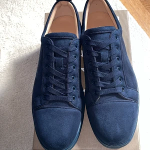 Loubs mörkblåa - Snygga marinblå sneakers från Bontoni i lyxig mocka med rund tå och klassisk snörning. Skorna har en unik röd sula med Bontoni-logga och diskret broderad logga baktill. Perfekta för dig som gillar stilrena och exklusiva detaljer.