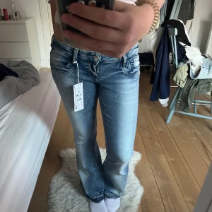 Scandi bootcut jeans från Gina Tricot - Säljer ett par Scandi low waist bootcut jeans från Gina Tricot i mellanblå tvätt. Jeansen har låg midja, klassisk femficksdesign och lätt utsvängda ben. Perfekta för dig som gillar en retro vibe och snygg passform. Jeansen är uppsprätta längst ned då jag tyckte de var korta på mig som är 170cm lång.