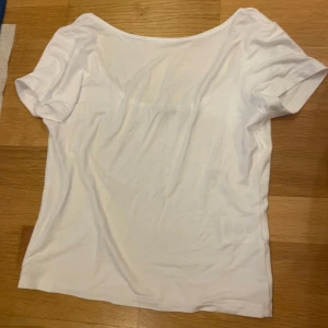 Vit basic topp med kort ärm - Enkel och stilren vit topp med rundad halsringning och korta ärmar.  Med öppen rygg