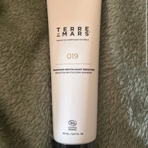 Terre de Mars 019 Revitalizing Shampoo - Terre de Mars 019 Revitalizing Shampoo i en stilren beige tub på 150 ml. Ekologiskt certifierad och framtagen med naturliga ingredienser för att ge håret en fräsch och återfuktad känsla. Perfekt för dig som gillar clean beauty och minimalistisk design.
