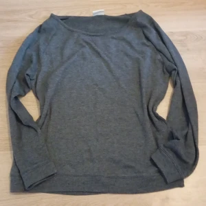 Mörkgrå långärmad tröja från Vila - En stilren mörkgrå långärmad tröja från Vila. Tröjan har en enkel, klassisk design med rund halsringning och mjukt material som känns skönt mot huden. Perfekt för lager-på-lager och passar till många olika outfits.