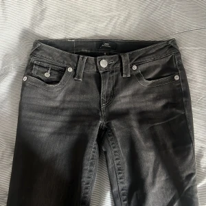 True Religion Jeans - Snygga mörkgrå jeans från True Religion, modell Joey LR Flare Flap. Byxorna har bootcut/flare passform och låg midja. Lite stora för mig men använda ett fåtal gånger! Om någon skulle ha en w24 i samma modell så är jag öppen för att byta. Har pälsdjur, kontakta mig vid intresse!❣️