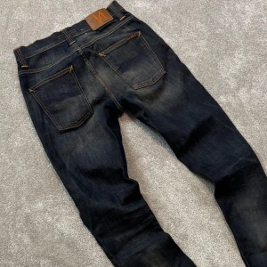 Nudie Grim Tim - Tja! Säljer dessa riktigt schyssta mörkgrå Nudie ”Grim Tim” jeansen med unik tvätt! Jeansen är i gott skick och har en slim/straight passform. Size 30/34. Skriv vid funderingar!