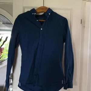 Mörkblå skjorta från Zara Man slim fit - Snygg mörkblå skjorta från Zara Man i slim fit-modell. Skjortan har klassisk krage med knappar, långa ärmar och stilren design. Perfekt för dig som gillar en enkel men modern look. Tillverkad i bomull för skön känsla hela dagen.