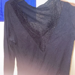 Mörkblå långärmad topp med spets - Mörkblå långärmad topp med djup v-ringning och snygga spetsdetaljer längs halsringningen. Tunn och mjuk i materialet, perfekt för lager-på-lager eller som statement-piece. Enkel att styla till både jeans och kjol.